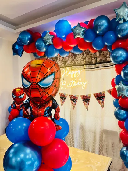 Here is a classic Spider-Man theme, perfect for a young superhero's birthday. The decoration is built around a bold red and blue balloon arch with star accents, a large Spider-Man foil balloon, and a 'Happy Birthday' neon sign.