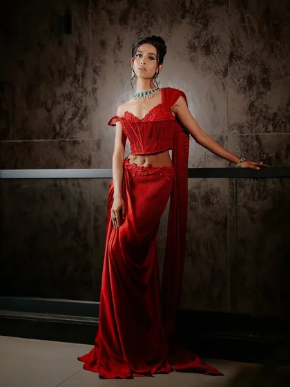 A full-length view of the ruby red corset sari, showcasing how the structured corset provides a powerful anchor to the flowing drape.