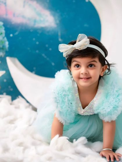 Crawling on clouds. The celestial backdrop and fluffy cloud props create a magical and ethereal world for this beautiful portrait.