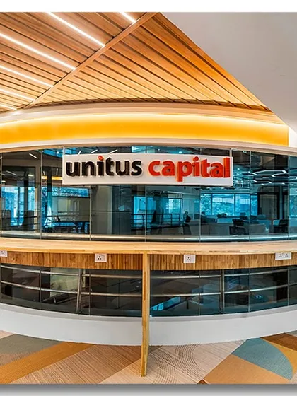 This shot captures the dynamic and collaborative spirit of the Unitus Capital office in Bangalore. The circular, glass-encased meeting space serves as a central hub, while the warm wood tones and geometric flooring create a modern and energetic corporate environment.