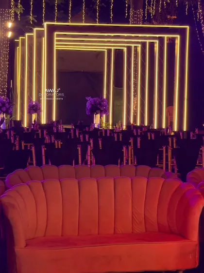 A comfortable and stylish lounge area for guests, with a modern orange sofa set against a backdrop of geometric neon lights.
