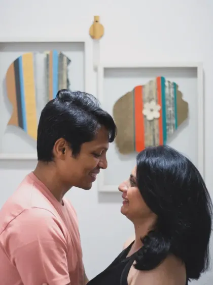 A sweet, smiling portrait of the couple at home, with interesting wall art in the background adding a personal touch to their lifestyle session.