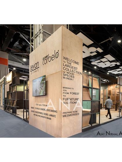 A side view of the Realply '23 exhibition space, showing how the layered facade and open aisle create an inviting path for visitors. The design effectively draws people in from the main walkway.