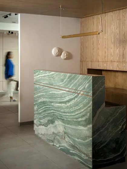 A full view of the stunning green marble reception desk. Paired with a minimalist linear pendant light and subtle wall art, it makes a powerful first impression.