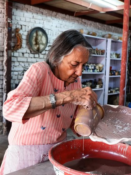 A student carefully applies glaze to her work. The application of glaze is a key step that determines the final color and texture of the Raku piece.