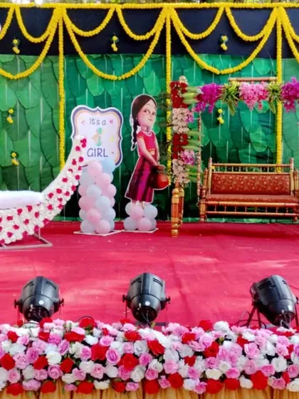 This outdoor baby shower decoration shows how I adapt my designs for different environments. The stage includes a floral moon prop, a decorated swing, and character cutouts, all set against a green and yellow backdrop for a daytime event.