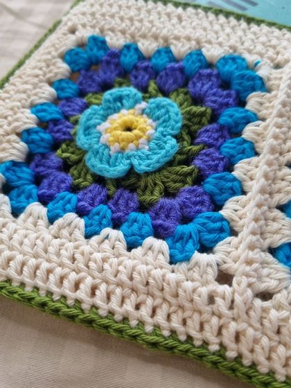 A close-up shot highlighting the intricate, layered petals of the 3D crochet flower.