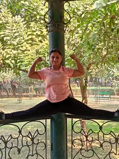 A middle split, or Samakonasana, on a park fence. This pose is a deep stretch for the inner thighs and requires consistent practice to achieve.
