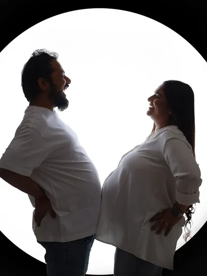 A playful silhouette shot where the husband-to-be mimics a baby bump. This shows the fun and humorous side of the pregnancy journey.