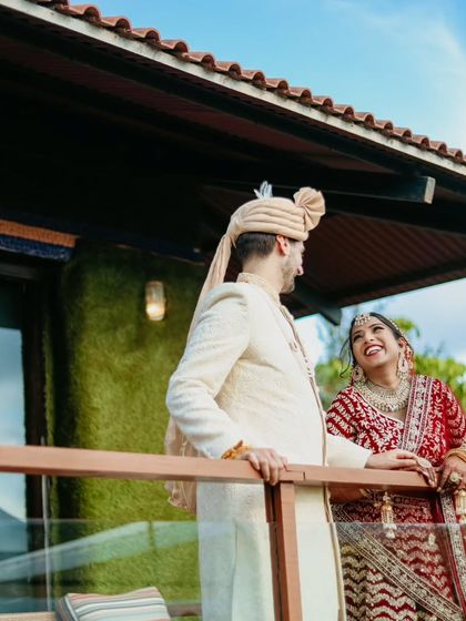 A candid moment of shared laughter on a balcony, with a beautiful natural backdrop.