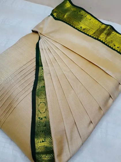 An elegant beige tussar silk saree with a dark green border.