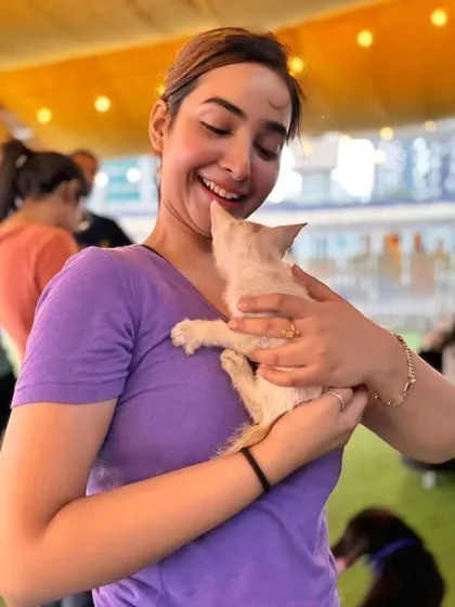 A participant smiles as she holds a tiny, fluffy white kitten, a look of pure delight on her face.