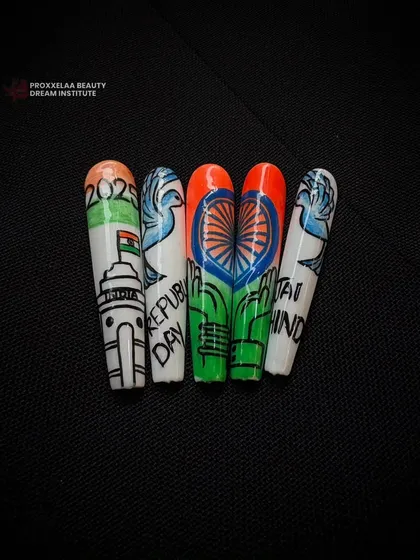 The finished set of hand-painted Republic Day nails, featuring iconic symbols like India Gate and the tricolor flag, all on long coffin-shaped extensions.