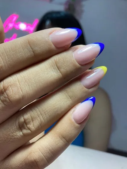 A custom colored French manicure featuring royal blue and yellow tips on almond-shaped nails.