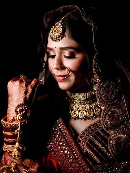 A close-up capturing the intricate details of the bridal makeup and jewelry. The gold eyeshadow makes her eyes pop.