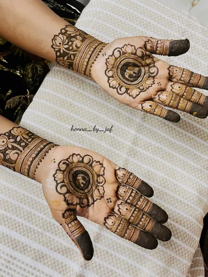 A beautiful bridal design with a central floral mandala on each palm. The fingers are decorated with simple bands and the wrists have a wide, detailed floral cuff.