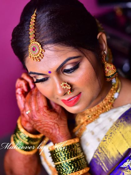 A detailed shot of the bride's makeup and jewellery. Notice the sharp eyeliner, the perfectly placed bindi, and the intricate details of her temple jewellery.