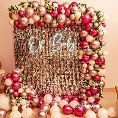 I combine different textures to create eye-catching backdrops. Here, a rose gold shimmer wall is framed by an organic balloon garland in shades of pink and rose gold, with an "Oh Baby" neon sign making it a perfect spot for photos.