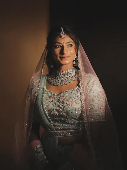 A stunning portrait of the bride Mansi, with dramatic lighting highlighting her features and pastel lehenga. This shows my ability to create artistic and moody bridal shots.