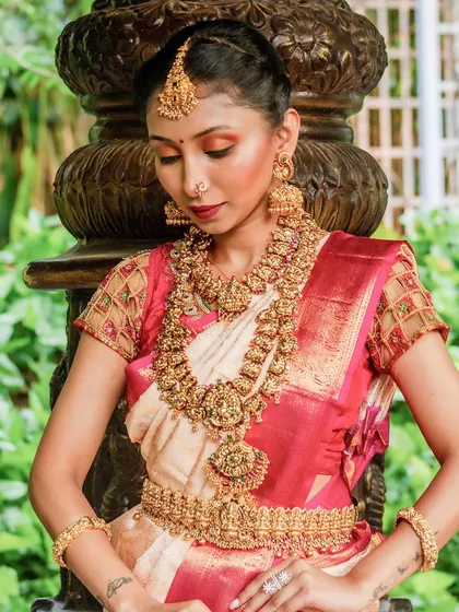 A detailed close up of our temple jewellery set, showing the intricate carvings on the necklace and the design of the large jhumka earrings.
