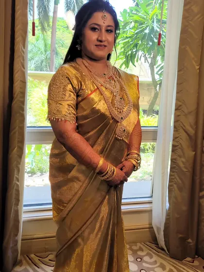 Bride Shruti looks absolutely regal in this Gold Kanjeevaram Tissue saree for her Muhurtham ceremony. The pre-pleated drape complements her stunning temple jewelry perfectly.
