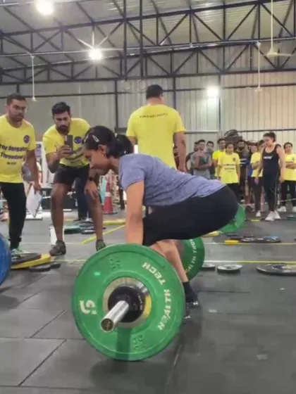 An athlete sets up for a heavy deadlift during the competition, with judges and fellow competitors watching closely.