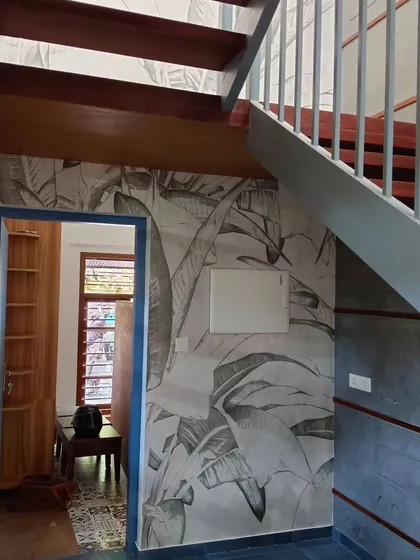 A stairway wall is a great opportunity for a continuous design. This grey-scale banana leaf wallpaper adds texture and visual interest to the space under the stairs, making it a thoughtful design element.