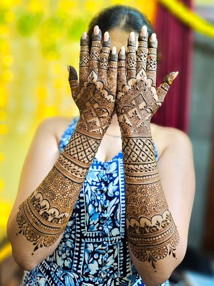 A happy bride showing off her full wedding henna, a perfect accessory for her special day.
