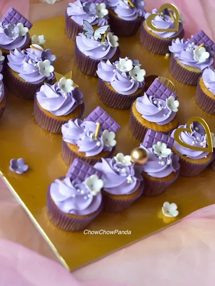 This image shows the details of the purple cupcakes, including the piped swirls and tiny white and gold pearl sprinkles.