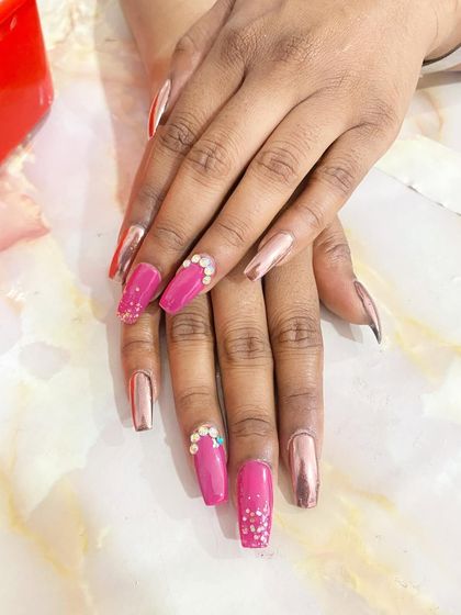 A beautiful combination of glossy pink and rose gold chrome nails. The pink nails are decorated with pearl and rhinestone clusters for a touch of elegance.