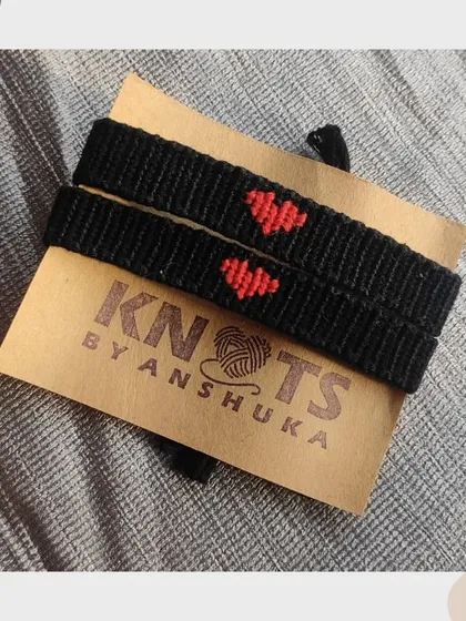 A pair of black friendship bracelets with a simple red heart in the center. It's a subtle and sweet way to have a matching set.