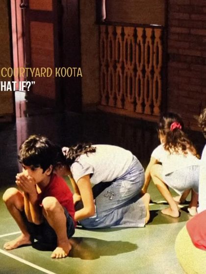 A candid shot from the "What If?" children's theatre workshop, showing young participants deeply engaged in a performance exercise. We believe in learning through play and creative expression.