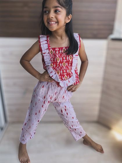 I love bringing traditional prints into everyday wear. This set features a beautiful red ikat pattern on the top with playful frills, paired with comfy striped pants. It’s a unique blend of ethnic charm and modern comfort.