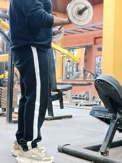 Using the barbell for a standing curl. Free weights are essential for building foundational strength and muscle mass.