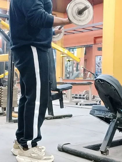 Using the barbell for a standing curl. Free weights are essential for building foundational strength and muscle mass.