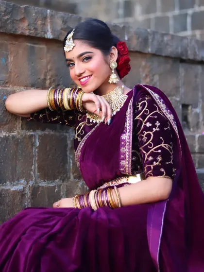 This bride chose a luxurious purple velvet saree for her reception. The look is completed with a classic floral bun, a statement choker, and glowing makeup.