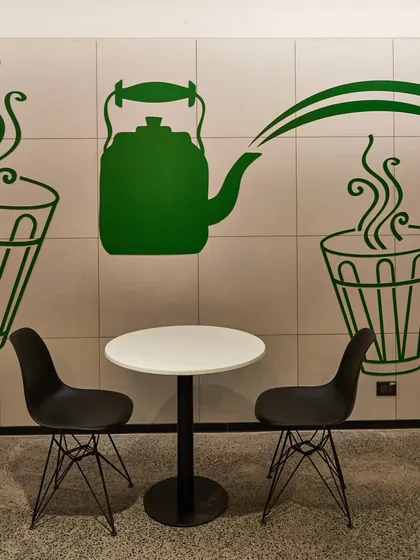A minimalist graphic of a chai kettle and glasses on a tiled wall. This simple design element adds a touch of local culture to a small breakout space.