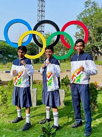 Our three young champions posing near the Olympic rings, a symbol of their ultimate dream.