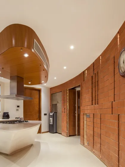 This kitchen in our Outré House project demonstrates our love for handmade details and unconventional forms. The curved terracotta brick wall and custom-designed island and chimney hood break away from straight lines to create a space that is both functional and sculptural.