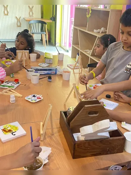 A group of children completely absorbed in their canvas painting activity. Our workshops are a great way for kids to express their creativity.