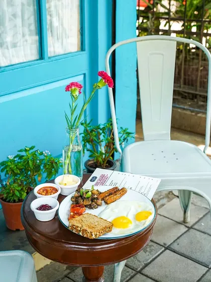 A classic English breakfast plate set on a small table outside a charming cafe with a blue door. This shot creates a serene and inviting atmosphere for a relaxed morning meal.