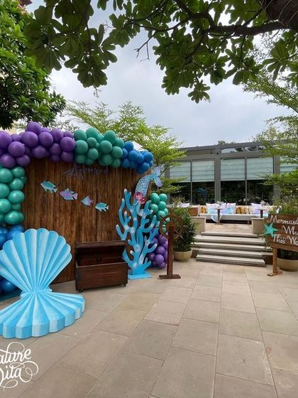 An outdoor photo spot with a giant seashell chair and a wooden backdrop, perfect for capturing memories of the mermaid party.