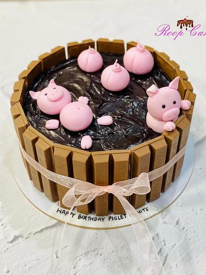A playful and delicious cake featuring cute fondant pigs relaxing in a "mud bath" of rich chocolate ganache. The tub is made from KitKat bars, making it a fun and indulgent treat.