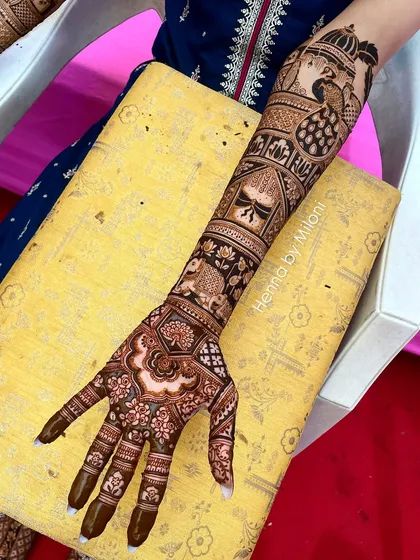 A full-arm bridal design with a variety of traditional motifs, including peacocks, elephants, and a kalash.