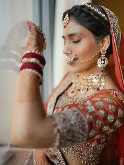 A serene moment by the window. This close up shot captures the bride's calm demeanor and the beautiful details of her nath and makeup.