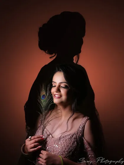 An artistic portrait of the bride-to-be with a peacock feather, her silhouette visible in the background.