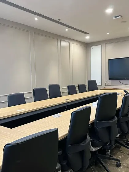 Functionality is paramount in this conference room design in Ambala. The space is equipped with a large wall-mounted screen for presentations, integrated power outlets in the U-shaped table, and neutral wall paneling to ensure a professional, distraction-free meeting environment.