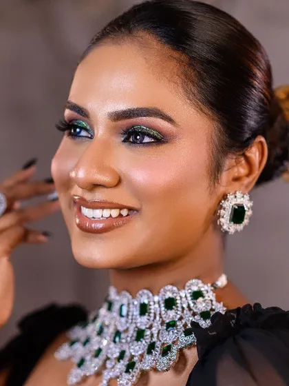 A close-up of a stunning green smokey eye and diamond jewelry. The lighting is perfectly calibrated to capture the sparkle of the gems and the rich pigment of the makeup.
