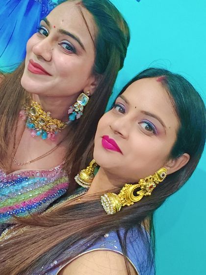 A fun selfie of two clients, one in a lavender sharara with gold jhumkas and the other in a colorful sequin lehenga with a modern choker.