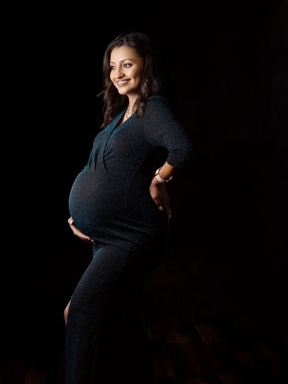 A low-key portrait where the light gently illuminates the mother's smile and baby bump. This technique creates a very intimate and serene feeling.